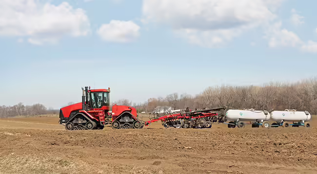 A red tractor applying fertilizer in a field. 