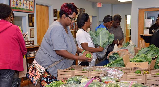 women serving fresh vegetables in food pantry line