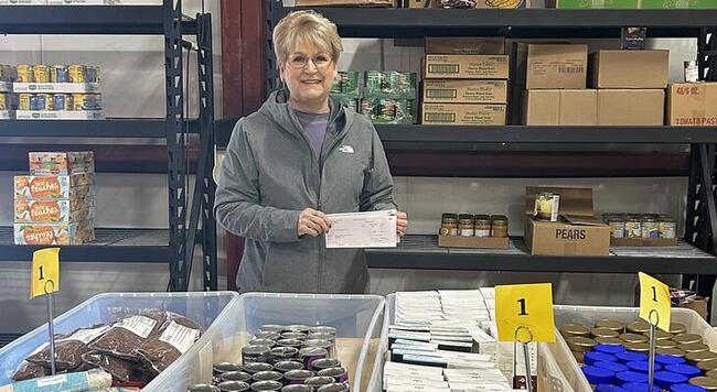lady standing in front of a table full of food pantry donations
