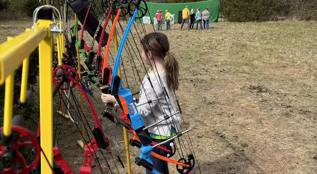 Child holding a bow at an archery range