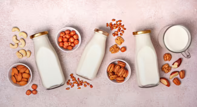 Image of cup of milk, bottles of milk, and different nuts and seeds