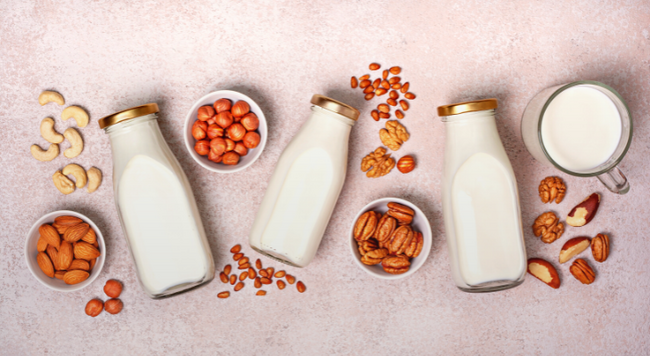 Image of cup of milk, bottles of milk, and different nuts and seeds