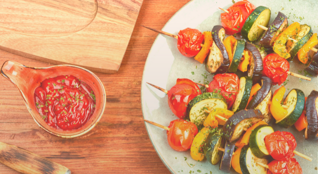 Grilled vegetables on skewers sitting on a plate.