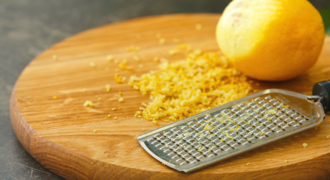 lemon and zester on a wooden cutting board