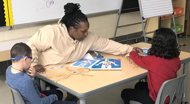 Teacher helps two students with project