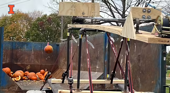orange pumpkin being launched into a dumpster