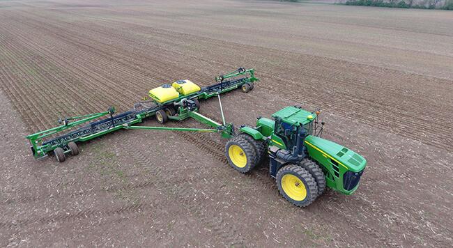 A tractor pulling a planter across a field. 