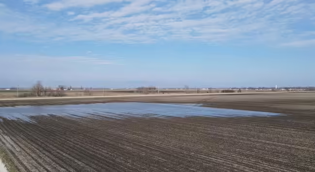An agricultural empty field with water standing in low areas