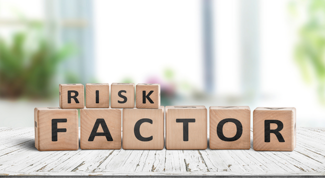 Image of wooden blocks spelling out Risk Factor with a blurred image of plants in the background