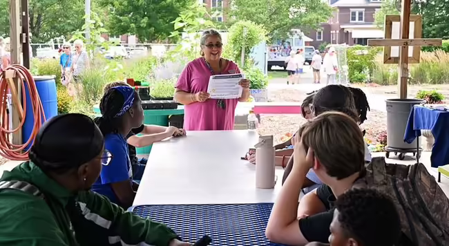Woman standing and speaking to a group of young people