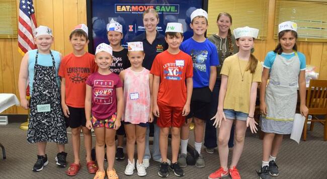 Kids taking a group photo with cooking hats on and some with aprons on