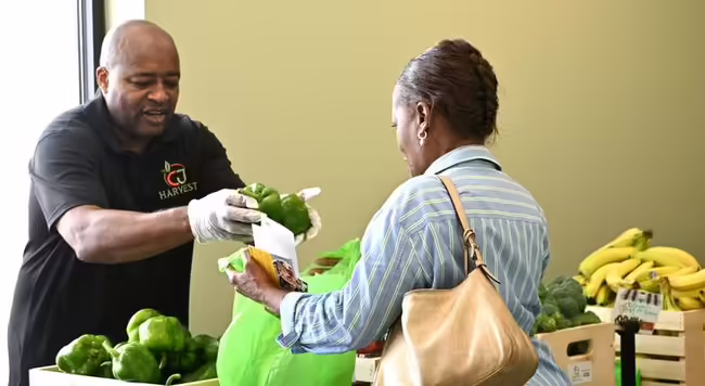 Man hands a woman some vegetables