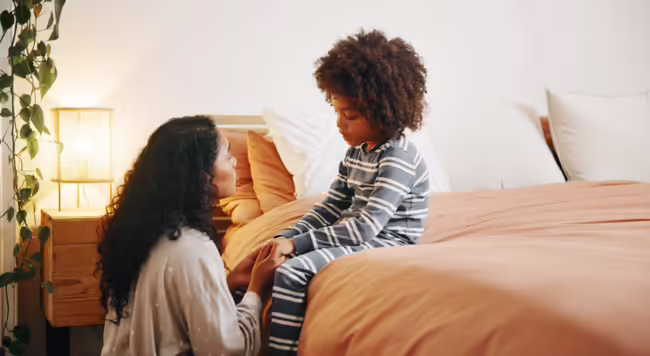 mother talking to child with child sitting on bed