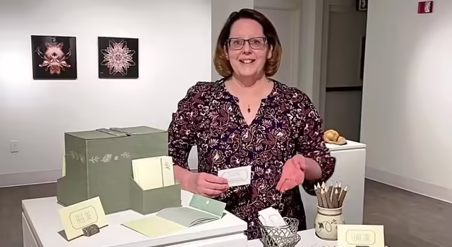 Peggy West standing next to her display at Peoria Art Guild