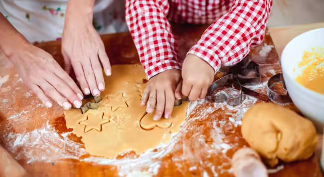adult and child using cookie cutters with dough
