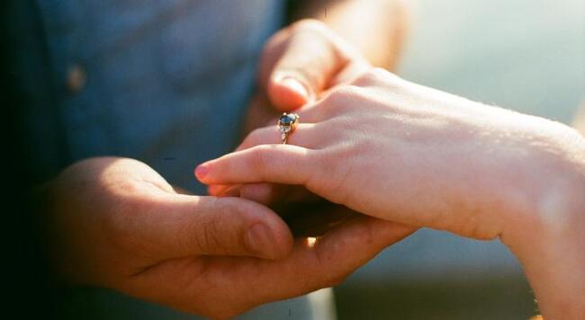 female hand with engagement ring held by another hand