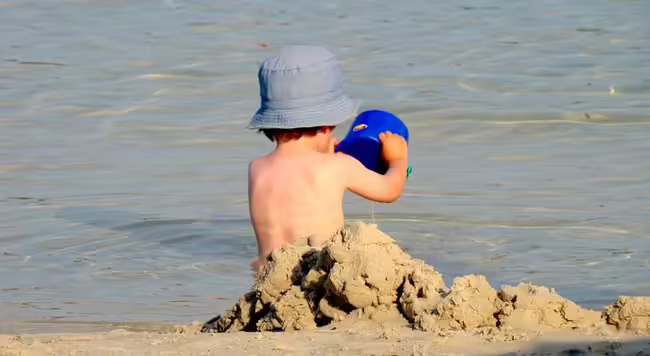 Little boy playing in sand on the beach