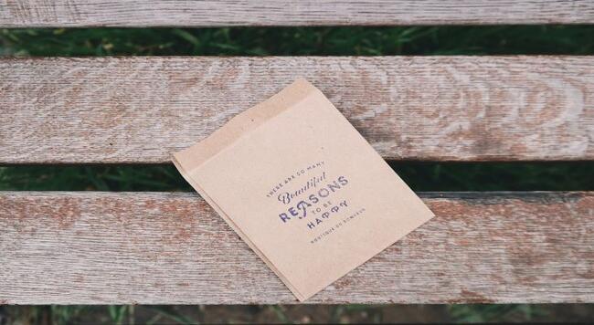bench with paper bag that has inspirational saying on it