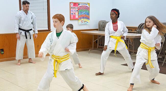 kids doing karate with teacher standing in background