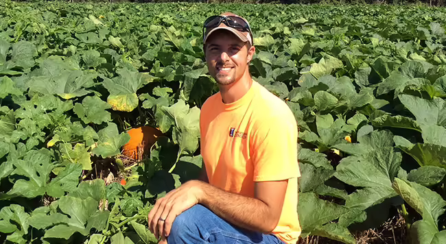 person kneeling in a pumpkin field