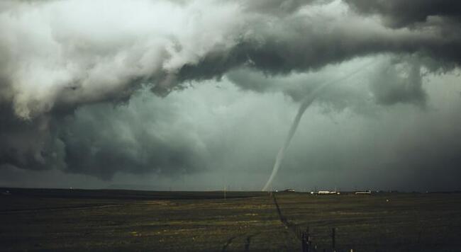 a tornado off in the distance surrounded by dark gray clouds 