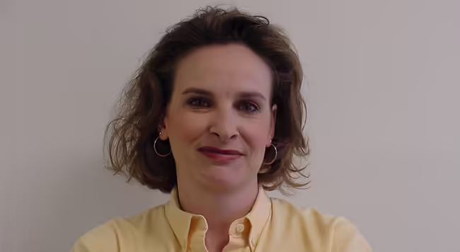 person with brown hair wearing a yellow shirt