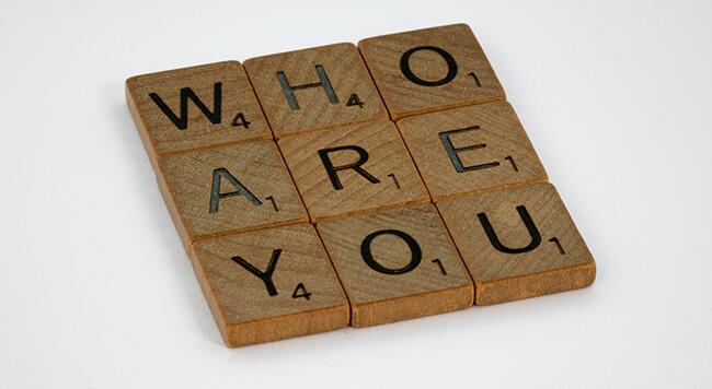 Scrabble pieces that spell out "who are you"