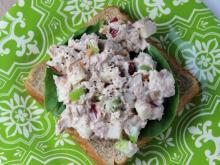 Tuna salad is on a piece of green lettuce on a slide of bread. The open-faced sandwich sits on a patterned green and white plate