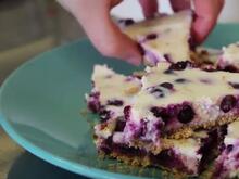 Hand reaching out to grab a slice of blueberry cheesecake
