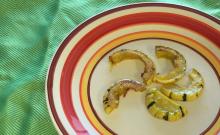Crescents of delicate squash in a circle shape on a red and yellow plate on a green placemat
