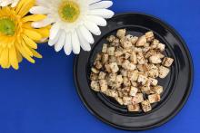 Black plate with roasted turnips on a blue background with yellow and white flowers
