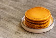 Stack of pumpkin pancakes on white plate on wood table