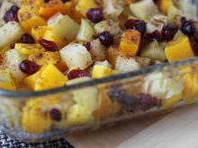 Glass casserole dish filled with squash, apples, and dried cranberries