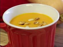 Squash soup in a red mug with a blurred background of a butternut squash