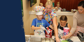 Youth participating in 4-H Cooking 101 school with assistance from our summer intern.