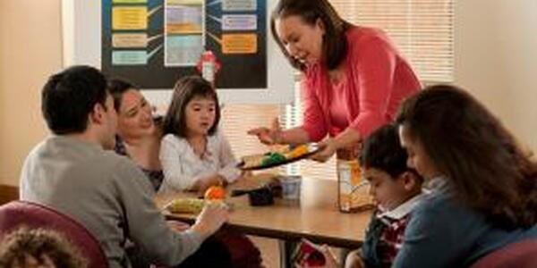 woman teaching a group of families about nutrition around a table