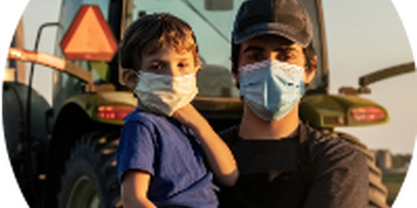 farmer and young boy wearing masks in front of tractor