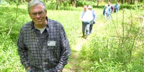 Master Naturalist walking on trail with others following behind