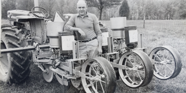 man standing in front of old tractor equipment