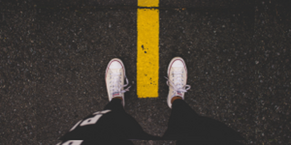Feet in white canvas shoes on each side of a yellow line
