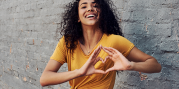 Happy young woman makes a heart with her hands
