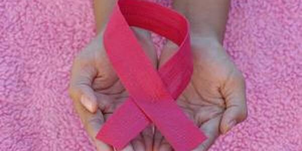Hands holding pink breast cancer awareness ribbon.
