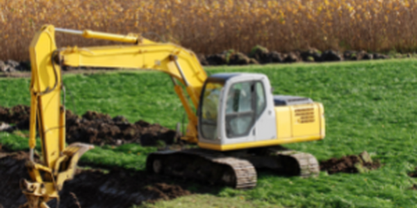 backhoe digging a trench in a field