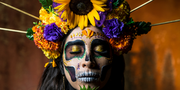 Hispanic woman wearing flower crown and dia de los muertos makeup