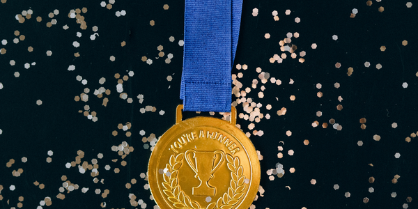 Picture of a gold medal in front of some glitter