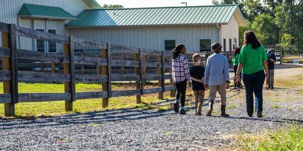 4-H member leads three younger members down a gravel path towards barn