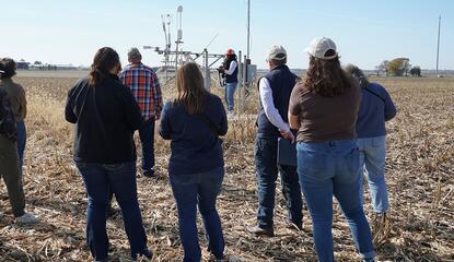 Group of people on a farm tour standing listening to a speaker 